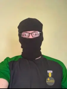 nate higgers, natejak, irl soyjaks, real mascots, 1 year on bald men with glasses website, balaclava, cosplay, front view, green clothes, irl background